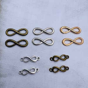 Puede incluir: Seis abalorios con forma de símbolo de infinito en tres acabados diferentes: plata, oro y bronce. Los abalorios están dispuestos en dos filas de tres.