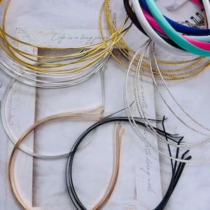 May include: A collection of gold, silver and black metal headbands. The headbands are arranged in a circle on a white surface. The text "Life is a long journey, but it is worth taking well" is visible in the background.
