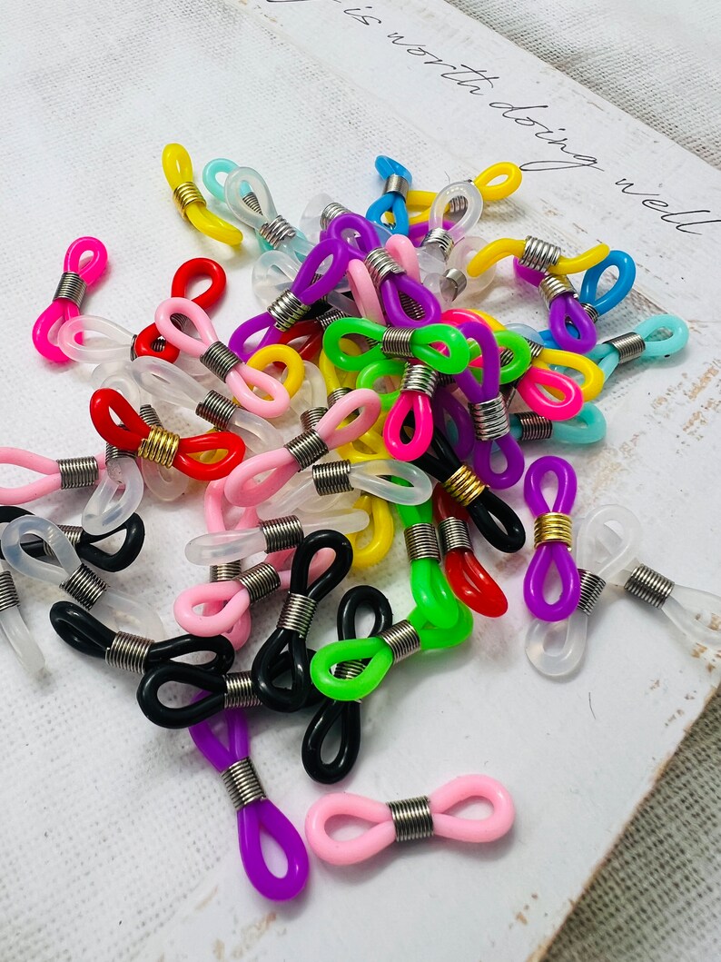 May include: Assortment of colorful plastic eyeglass chain holders with metal spring closures. The holders come in a variety of colors, including red, blue, green, yellow, pink, purple, and black.