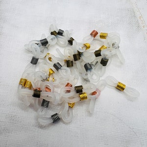 May include: A pile of clear plastic eyeglass chain holders with metal spring clips in gold, silver, copper, and black.