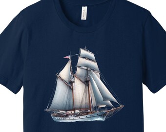 Puede incluir: Una camiseta azul marino con un gráfico de velero blanco. El velero tiene velas blancas y un casco marrón.