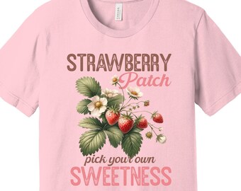 Op de afbeelding: Roze T-shirt met een afbeelding van aardbeien en de tekst "Strawberry Patch pick your own SWEETNESS".