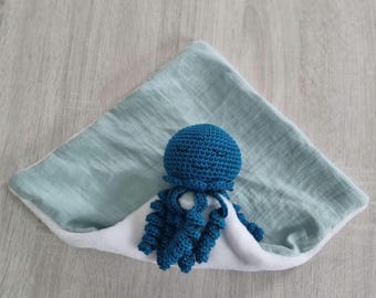 May include: A blue crocheted octopus toy on a light blue and white baby blanket.