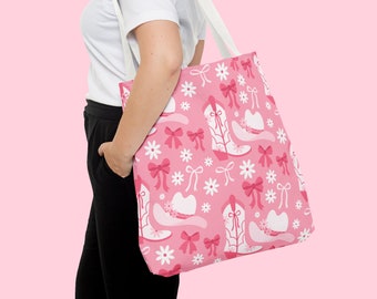 Op de afbeelding: Een roze tote bag met een witte band. De tas heeft een roze en wit patroon van cowboylaarzen, hoeden en bloemen.