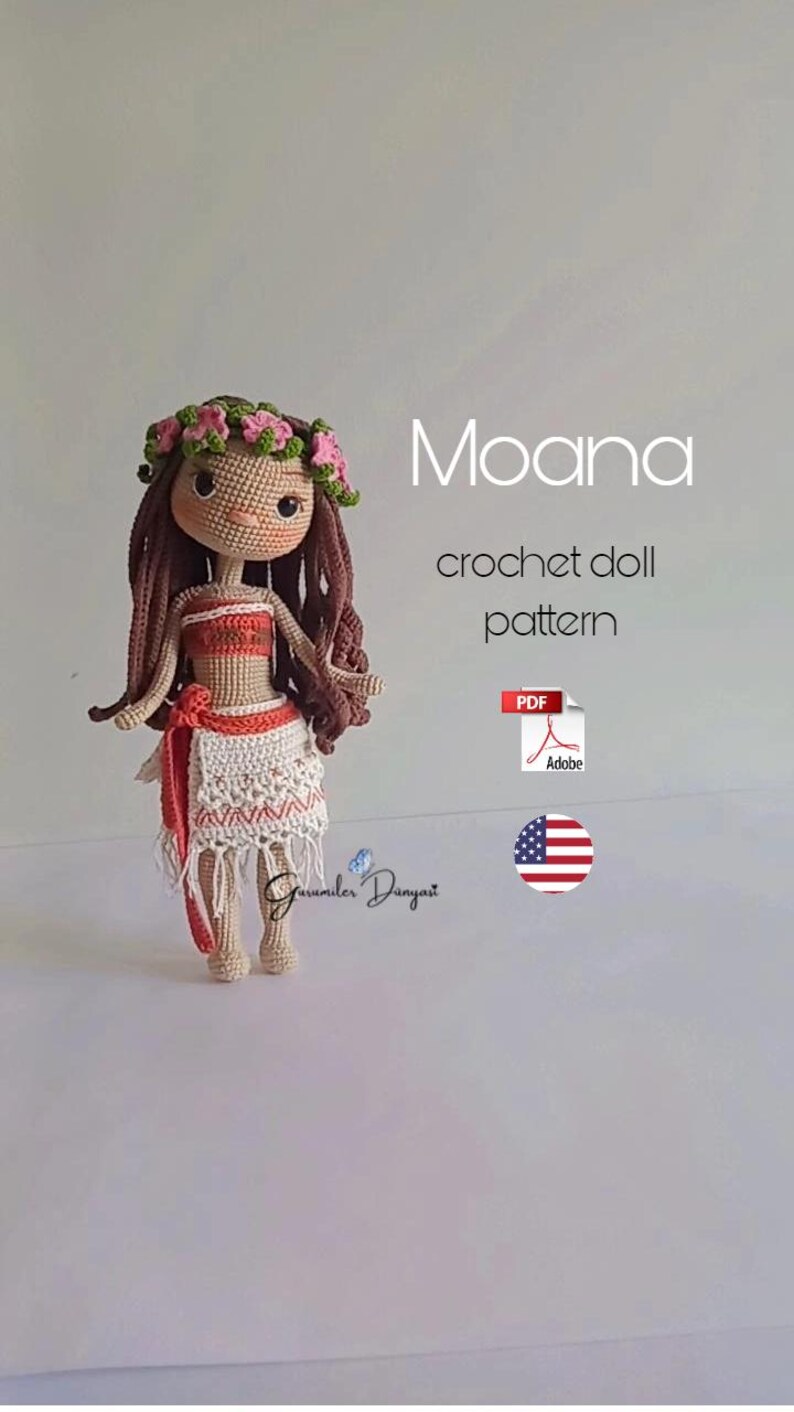 May include: Crochet doll pattern for a Moana doll. The doll is wearing a brown wig, a pink flower crown, a red and white top, and a white skirt with a red sash. The pattern is available as a PDF download. The image also includes the text "Moana crochet doll pattern" and a US flag.