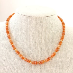 Peut inclure: Collier compos&eacute; de perles de pierres pr&eacute;cieuses orange avec des entretoises dor&eacute;es. Le collier est pr&eacute;sent&eacute; sur un buste de mannequin de couleur neutre. Les perles ont une forme irr&eacute;guli&egrave;re &agrave; facettes. C'est un bijou.