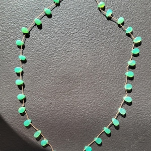 Pode incluir: Um delicado colar de corrente de ouro com uma s&eacute;rie de pedras preciosas verdes em forma de l&aacute;grima. O colar mede aproximadamente 45 cm de comprimento.