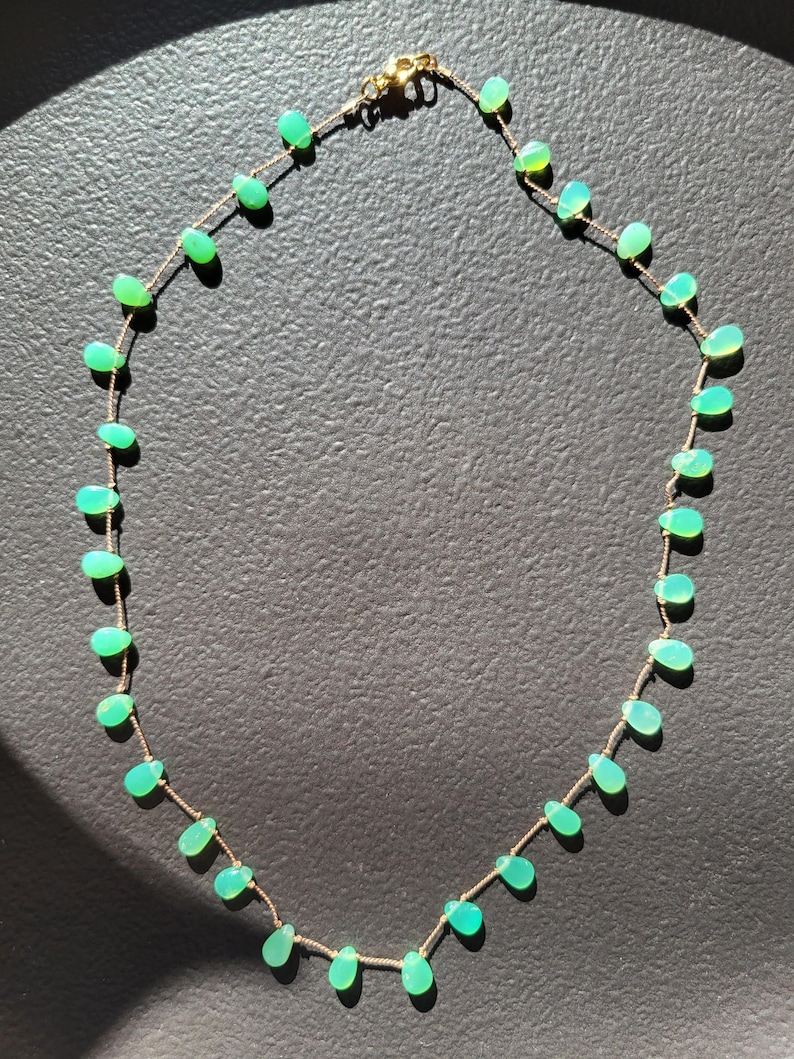 Pode incluir: Um delicado colar de corrente de ouro com uma s&eacute;rie de pedras preciosas verdes em forma de l&aacute;grima. O colar mede aproximadamente 45 cm de comprimento.
