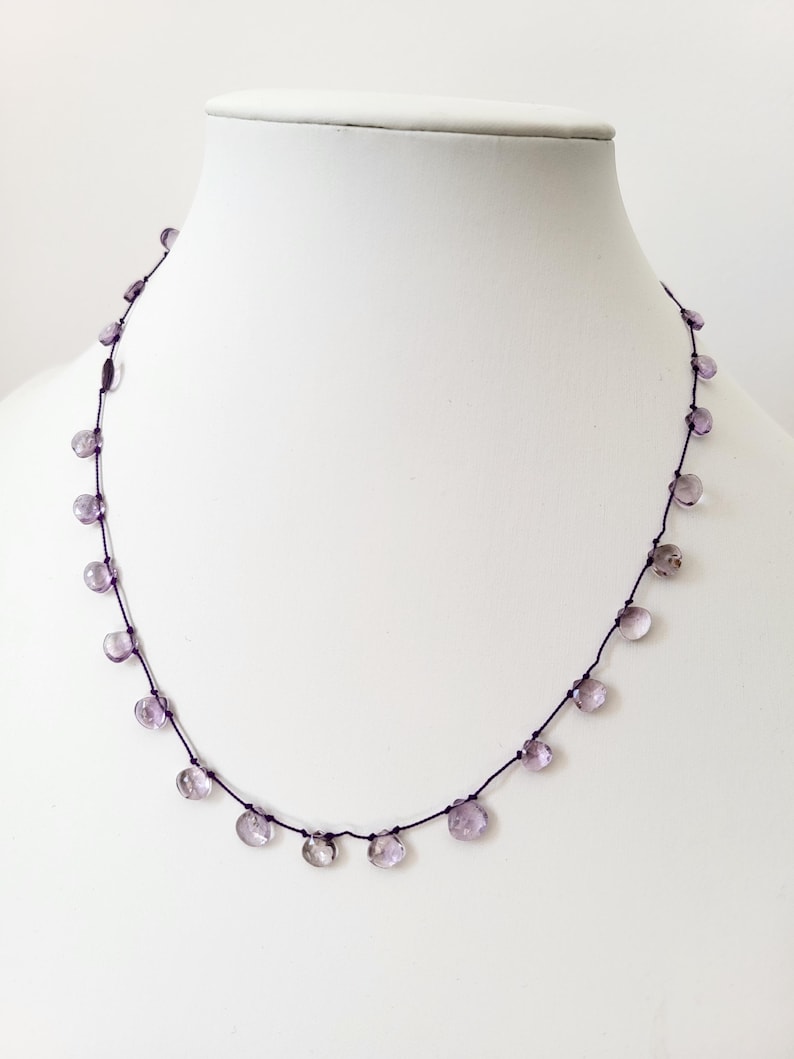 Op de afbeelding: Een delicate ketting met een paarse koord en kleine, lichtpaarse edelsteen kralen.