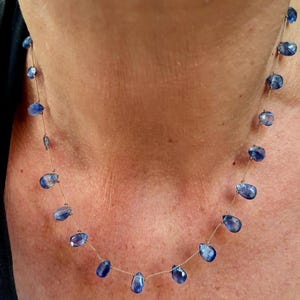 Puede incluir: Un collar delicado que presenta una cadena dorada fina intercalada con m&uacute;ltiples piedras preciosas azules peque&ntilde;as, facetadas y con forma de l&aacute;grima. Las piedras est&aacute;n espaciadas uniformemente a lo largo de la cadena, creando un efecto flotante.