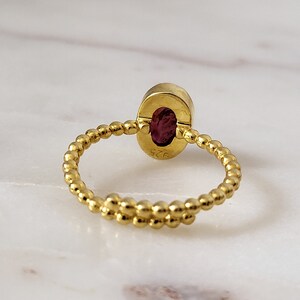 Puede incluir: Un anillo de oro con una banda retorcida y una piedra ovalada roja. El anillo est&aacute; marcado con el n&uacute;mero "925".