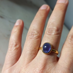 K&ouml;nnte beinhalten: Ein goldener Ring mit einem gro&szlig;en ovalen, violetten Edelstein.