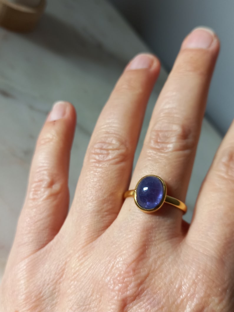 K&ouml;nnte beinhalten: Ein goldener Ring mit einem gro&szlig;en ovalen, violetten Edelstein.