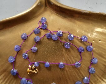 Necklace of natural blue-purple tanzanite stones, teardrop-shaped, knotted together with silk thread. Delicate, minimalist, fine necklace.