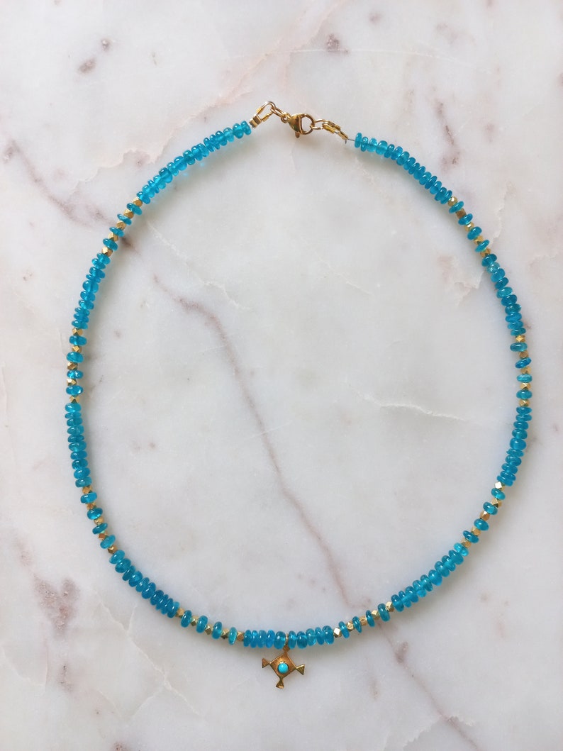 May include: A turquoise blue and gold beaded necklace with a small turquoise cross pendant.