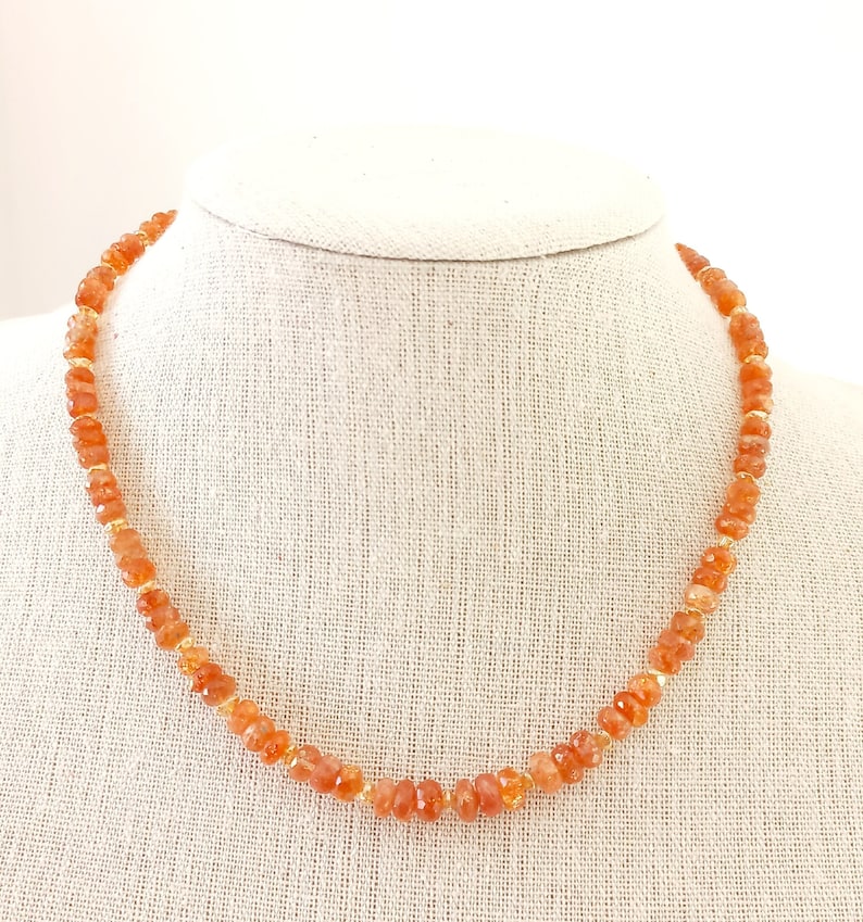 Peut inclure: Collier compos&eacute; de perles de pierres pr&eacute;cieuses orange avec des entretoises dor&eacute;es. Le collier est pr&eacute;sent&eacute; sur un buste de mannequin de couleur neutre. Les perles ont une forme irr&eacute;guli&egrave;re &agrave; facettes. C'est un bijou.
