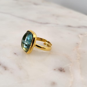 May include: Gold ring with a large, square, blue gemstone.