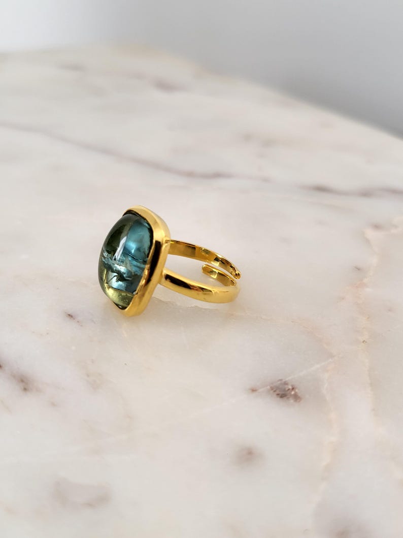 May include: Gold ring with a large, square, blue gemstone.