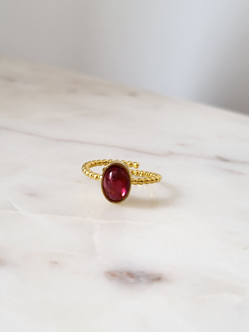 Puede incluir: Un anillo de oro con una piedra ovalada roja. El anillo est&aacute; hecho de peque&ntilde;as cuentas doradas.