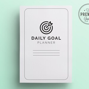 K&ouml;nnte beinhalten: Ein wei&szlig;er Daily Goal Planner mit einem schwarzen Ziel- und Pfeilsymbol. Der Planer hat den Text "DAILY GOAL PLANNER" und drei horizontale Linien f&uuml;r Notizen. Ein kreisf&ouml;rmiges Siegel "The Premium Quality" befindet sich in der oberen rechten Ecke.
