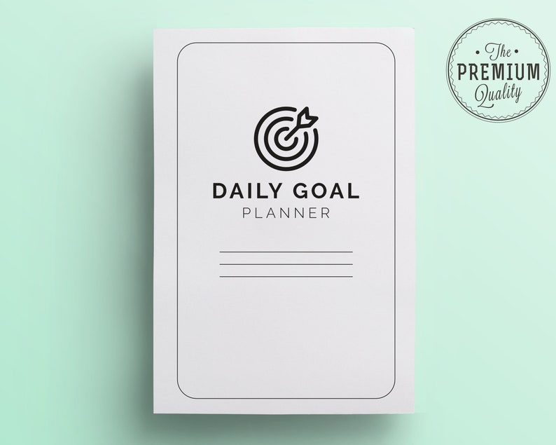 K&ouml;nnte beinhalten: Ein wei&szlig;er Daily Goal Planner mit einem schwarzen Ziel- und Pfeilsymbol. Der Planer hat den Text "DAILY GOAL PLANNER" und drei horizontale Linien f&uuml;r Notizen. Ein kreisf&ouml;rmiges Siegel "The Premium Quality" befindet sich in der oberen rechten Ecke.