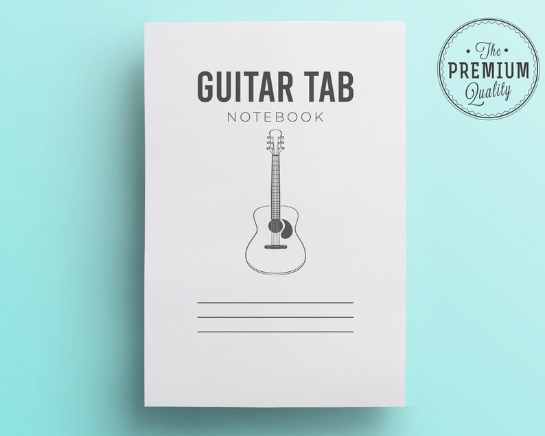 May include: A white Guitar Tab Notebook with a black line drawing of an acoustic guitar. The notebook has the words "GUITAR TAB NOTEBOOK" printed in black. A circular "The Premium Quality" seal is in the upper right corner.
