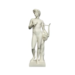 以下が含まれることがあります： 竪琴を弾いている人の白い石膏像。像は長方形の台座の上に立っている。