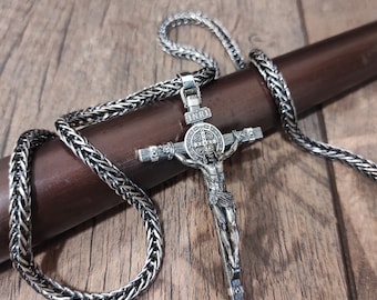 Könnte beinhalten: Eine silberne Kettenkette mit einem silbernen Kreuzanhänger. Das Kreuz zeigt eine Figur von Jesus Christus und die Inschrift "INRI".