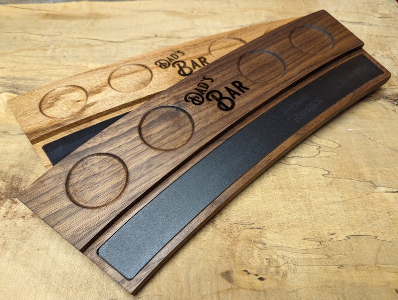 May include: A wooden serving tray with a black chalkboard insert. The tray has four cup holders and is engraved with the text "Dad's Bar".