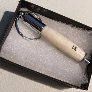 antler cigar plug cutter keychain in a box with the letter "lk" engraved on it