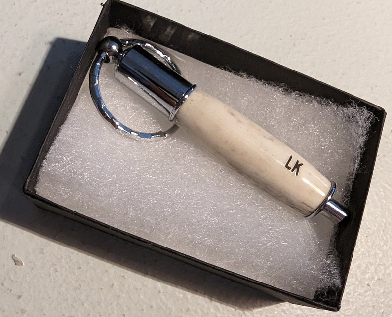 antler cigar plug cutter keychain in a box with the letter "lk" engraved on it
