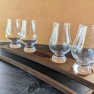 May include: A wooden tray with a black leather insert and four clear glass whiskey glasses. The tray is engraved with the word "Shauntee".