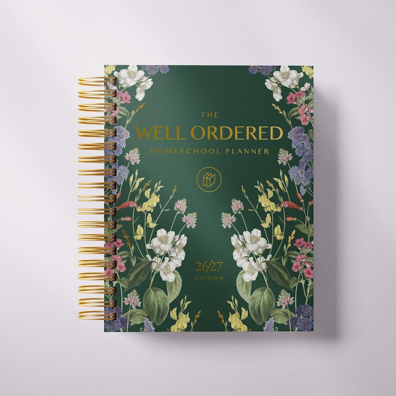 May include: A spiral-bound homeschool planner with a dark green cover. The cover features the text "THE WELL ORDERED HOMESCHOOL PLANNER" and is adorned with floral illustrations in white, pink, yellow, and purple. The edition is 26/27.