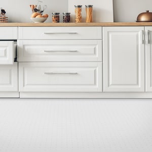 Puede incluir: Armarios de cocina blancos con tres cajones y dos puertas. Los armarios están cerrados, excepto el cajón superior izquierdo, que está abierto. Los armarios están colocados contra una pared blanca con un suelo de baldosas blancas.