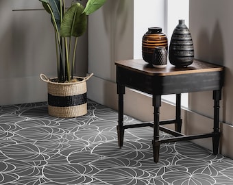 May include: A black side table with a wooden top and three legs. The table is decorated with three ceramic vases, one brown with black stripes, one black with white stripes, and one small, round, gray vase. The table is sitting on a black and white patterned floor.