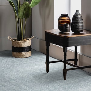 Puede incluir: Una mesa auxiliar negra con una tapa de madera y patas torneadas. Tres jarrones decorativos están sobre la mesa, uno con rayas marrones y negras, otro con un patrón gris y negro, y otro con un patrón blanco y gris. Una planta en maceta con hojas verdes está en el fondo.