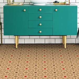Puede incluir: Un armario turquesa con patas doradas se encuentra frente a una pared de azulejos blancos. El armario tiene cuatro cajones y dos puertas. El suelo está cubierto de baldosas con un patrón de color marrón, rojo y blanco.