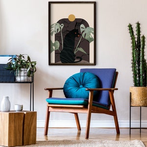 May include: A black panther illustration in a framed print with a dark green and brown background. The panther is sitting on a rock with a yellow sun behind it. The print is hanging on a white wall above a wooden chair with a blue cushion.