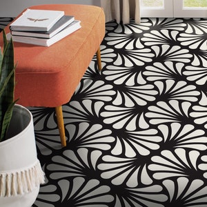 Peut inclure: Tapis de sol à motifs noirs et blancs avec un pouf blanc et orange et une plante en pot au premier plan.