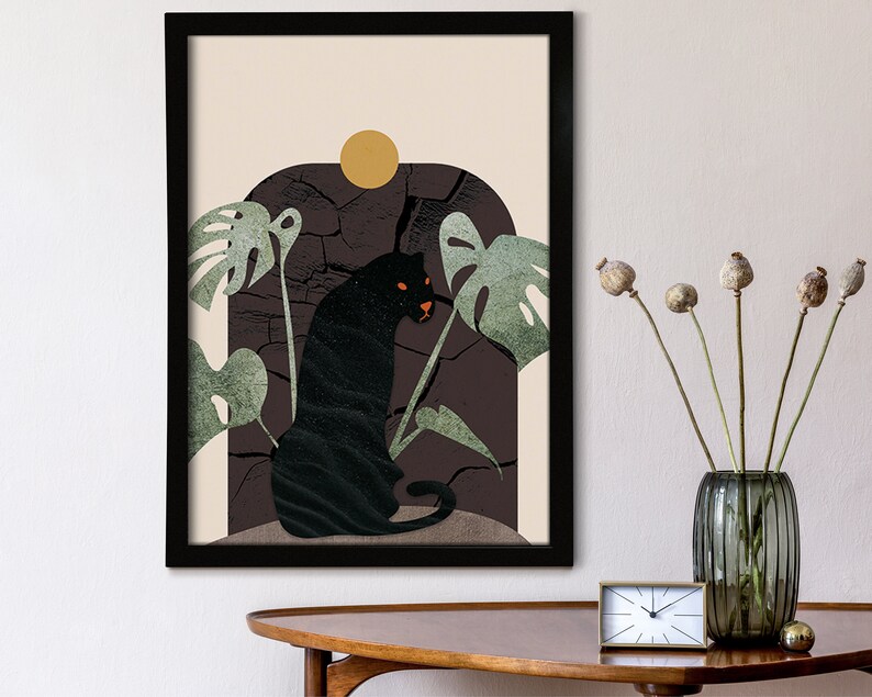 May include: A framed print with a black panther sitting in a jungle scene. The panther is surrounded by green leaves and a cracked brown rock. The background is a light beige color with a yellow sun.