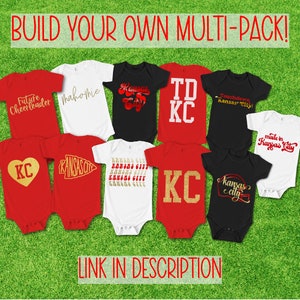 May include: A collection of ten baby onesies with various designs featuring the words "Kansas City" in different fonts and styles. The onesies are red, white, and black.