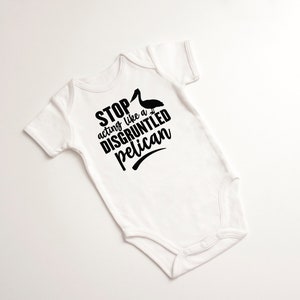 May include: White baby onesie with black text that reads "STOP acting like a DISGRUNTLED pelican" with a black silhouette of a pelican above the text.