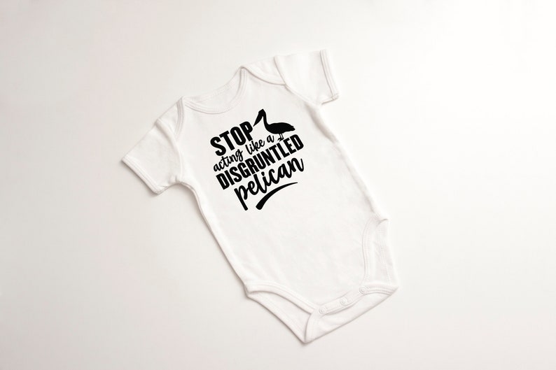 May include: White baby onesie with black text that reads "STOP acting like a DISGRUNTLED pelican" with a black silhouette of a pelican above the text.