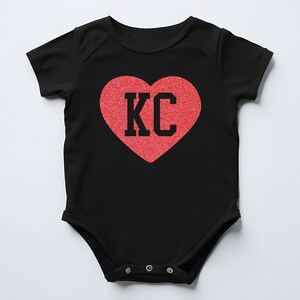 May include: Black baby onesie with a red heart that says "KC" in black letters.