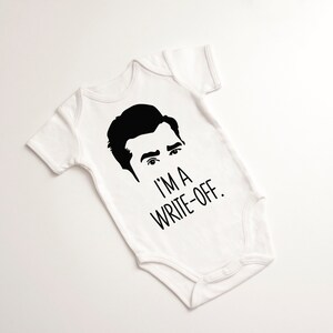 May include: White baby onesie with a black silhouette of a man's face and the text "I'm a write-off."