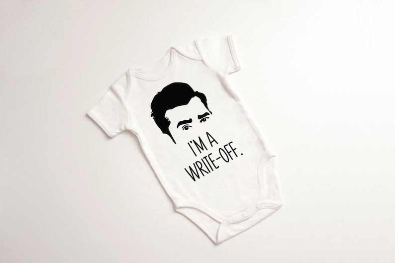 May include: White baby onesie with a black silhouette of a man's face and the text "I'm a write-off."