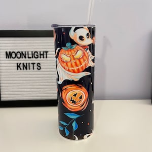 May include: A black and blue stainless steel tumbler with a Halloween themed design featuring pumpkins, ghosts, and leaves. The tumbler has a clear lid and a clear straw.