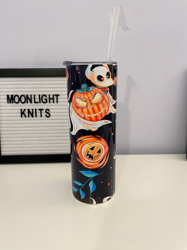 May include: A black and blue stainless steel tumbler with a Halloween themed design featuring pumpkins, ghosts, and leaves. The tumbler has a clear lid and a clear straw.