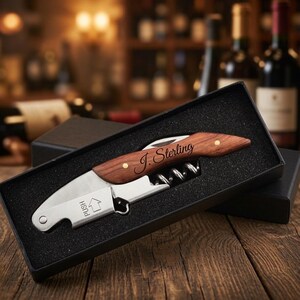 May include: A stainless steel waiter's corkscrew with a wood handle featuring the engraved name J. Sterling. The tool includes a metal lever with the word PUSH and an upward arrow, resting inside a black foam-lined rectangular gift box.
