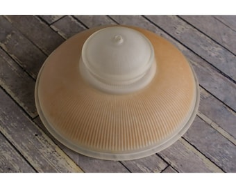 May include: A frosted glass lampshade with a ribbed design and a smaller, frosted glass dome on top. The lampshade is a light brown color.